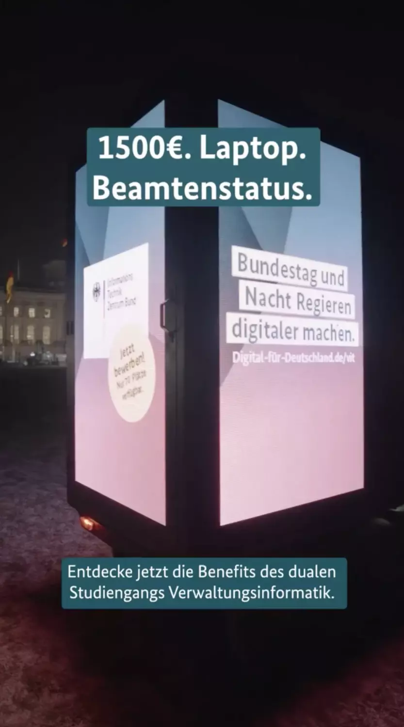 Videoausschnitt. Eine beleuchtete Reklamesäule. Darauf der Text 1500€ Laptop. Beamtenstatus.